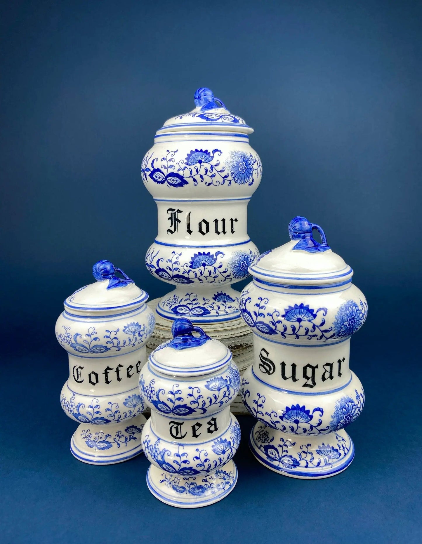 Decorative blue-and-white ceramic canister set with lids, labeled Coffee Sugar Tea Flour on Tampa Home & Garden Store