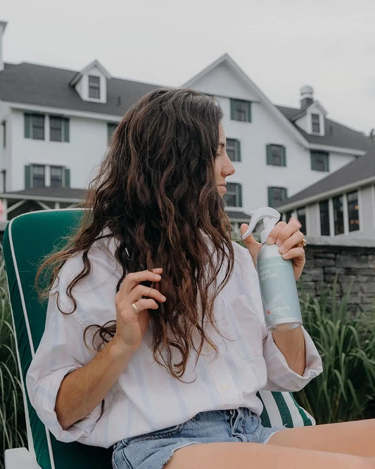 Hair Repair Leave-In Treatment 10 oz vegan bottle held by a woman with long wavy hair outdoors on Tampa Home & Garden Store