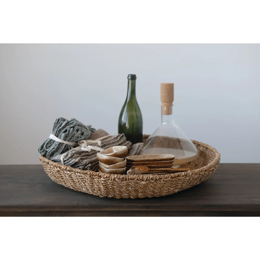 Artisan hand-woven seagrass display tray filled with bottles, bowls and textiles on Tampa Home & Garden Store