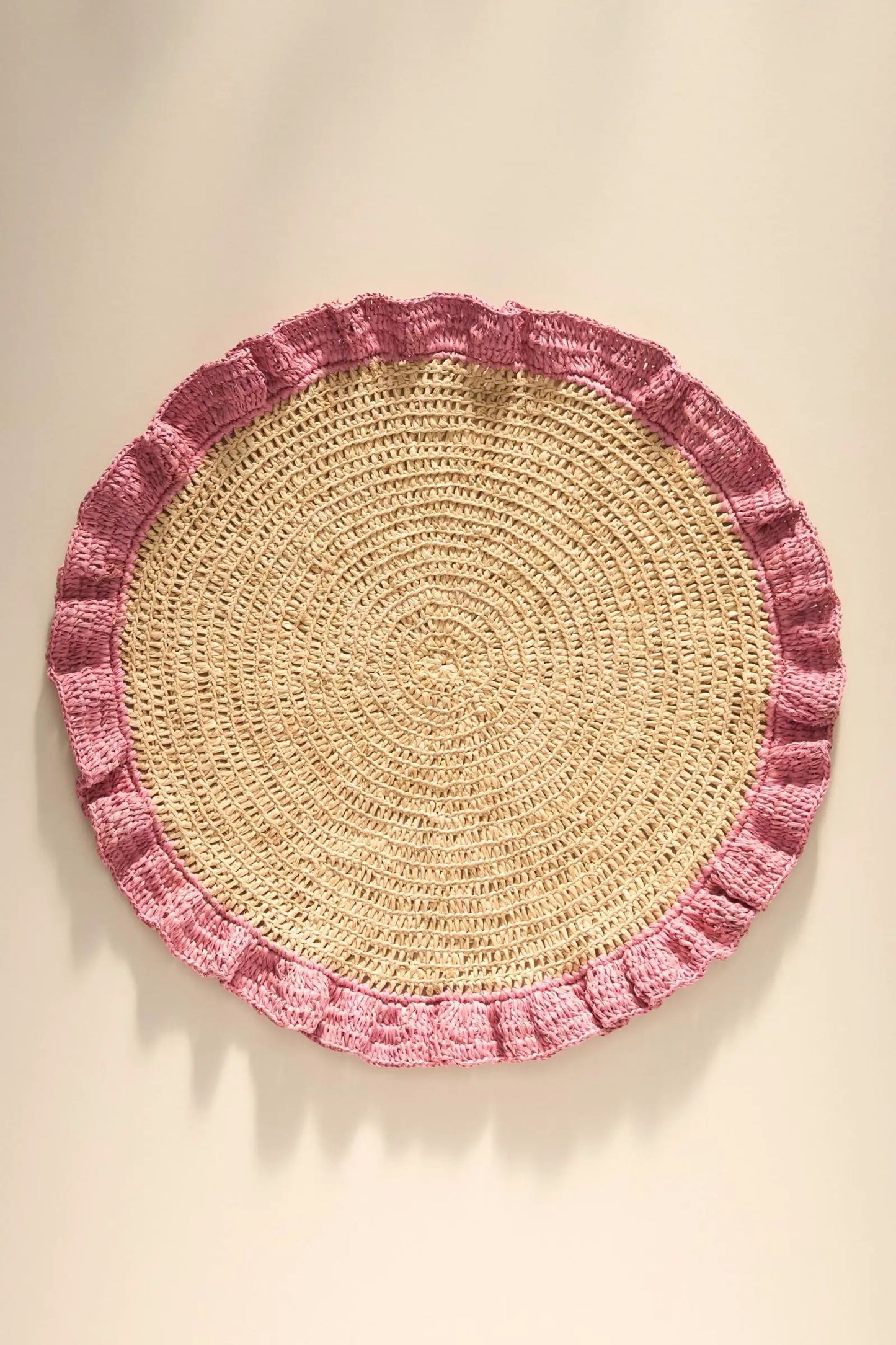 Round handwoven raffia placemat with pink ruffle edge for boho table decor on Tampa Home & Garden Store