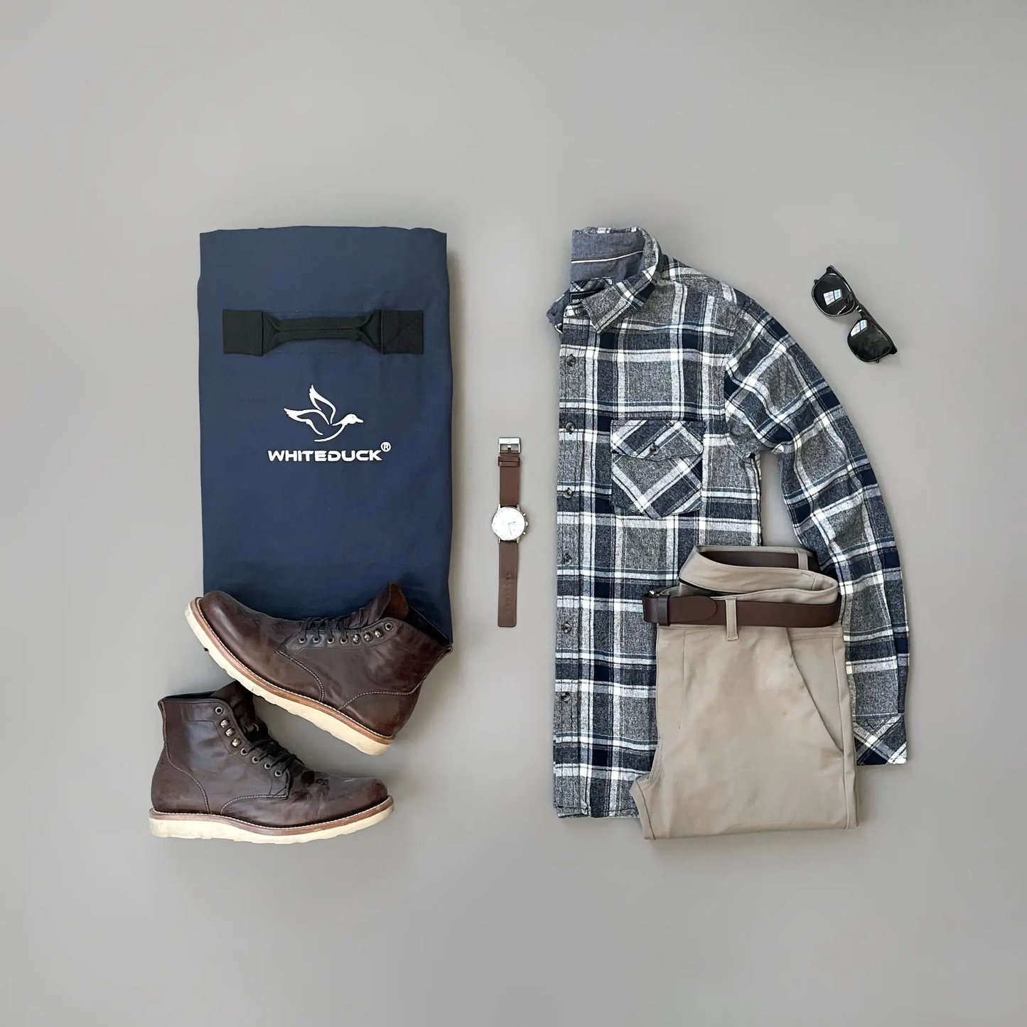 Hoplite Canvas Duffel Bag in navy with White Duck Outdoors logo, plaid shirt on Tampa Home & Garden Store