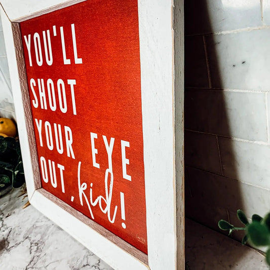 You'll Shoot Your Eye Out Sign in red with white lettering, rustic white frame Gia Roma on Tampa Home & Garden Store