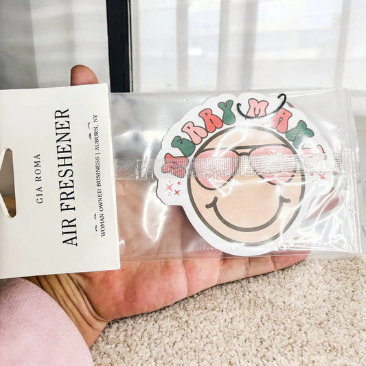 Air freshener hanging in clear package with round pink and green label, Gia Roma vehicle scent on Tampa Home & Garden Store