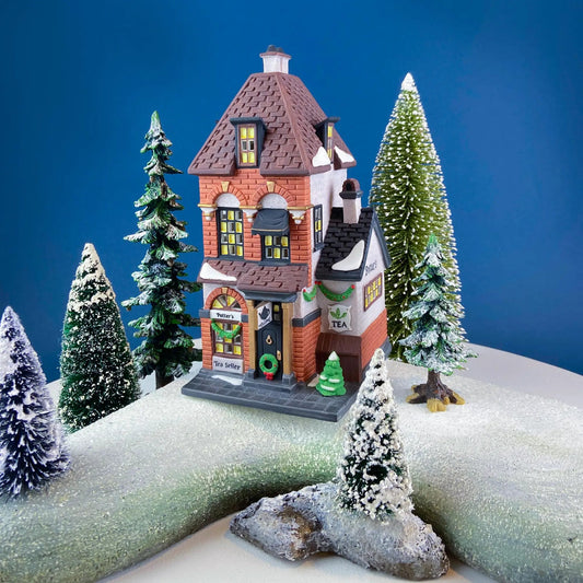 Illuminated Christmas Village Tea Seller House brick-red facade lit windows trees on Tampa Home & Garden Store