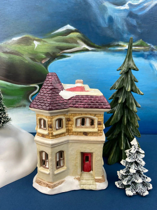 Illuminated porcelain house for Christmas village with red-tiled roof, stone facade, and snow base on Tampa Home & Garden Store