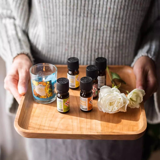 Natural Wood Plate Serving Tray with six essential oil bottles, a blue candle, and white roses on Tampa Home & Garden Store