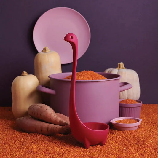 Jumbo Nessie soup ladle by OTOTO DESIGN, red silicone Nessie-shaped ladle beside a purple pot on Tampa Home & Garden Store