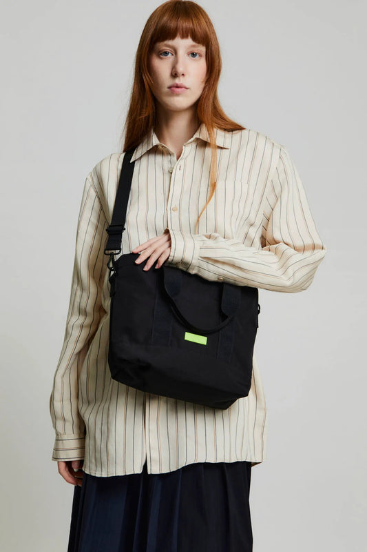 Strata Mini Tote Bag Lefrik USA black tote with lime green logo tag and shoulder strap on model on Tampa Home & Garden Store