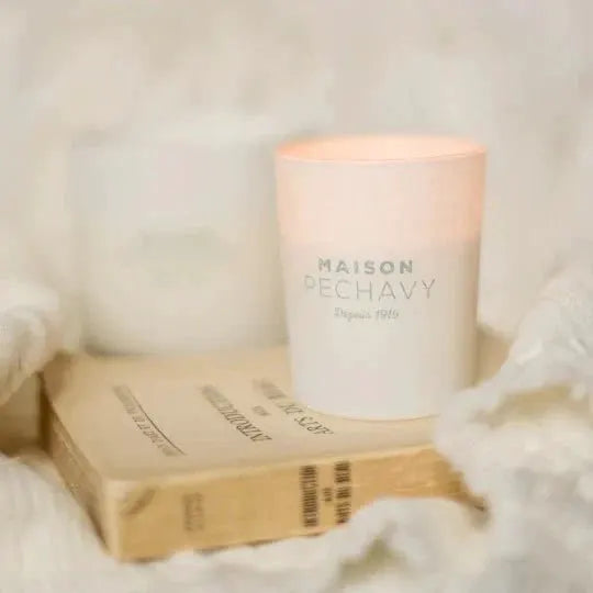 Lana Candle with Wood Fire Lavender Patchouli in a white container atop beige books on Tampa Home & Garden Store
