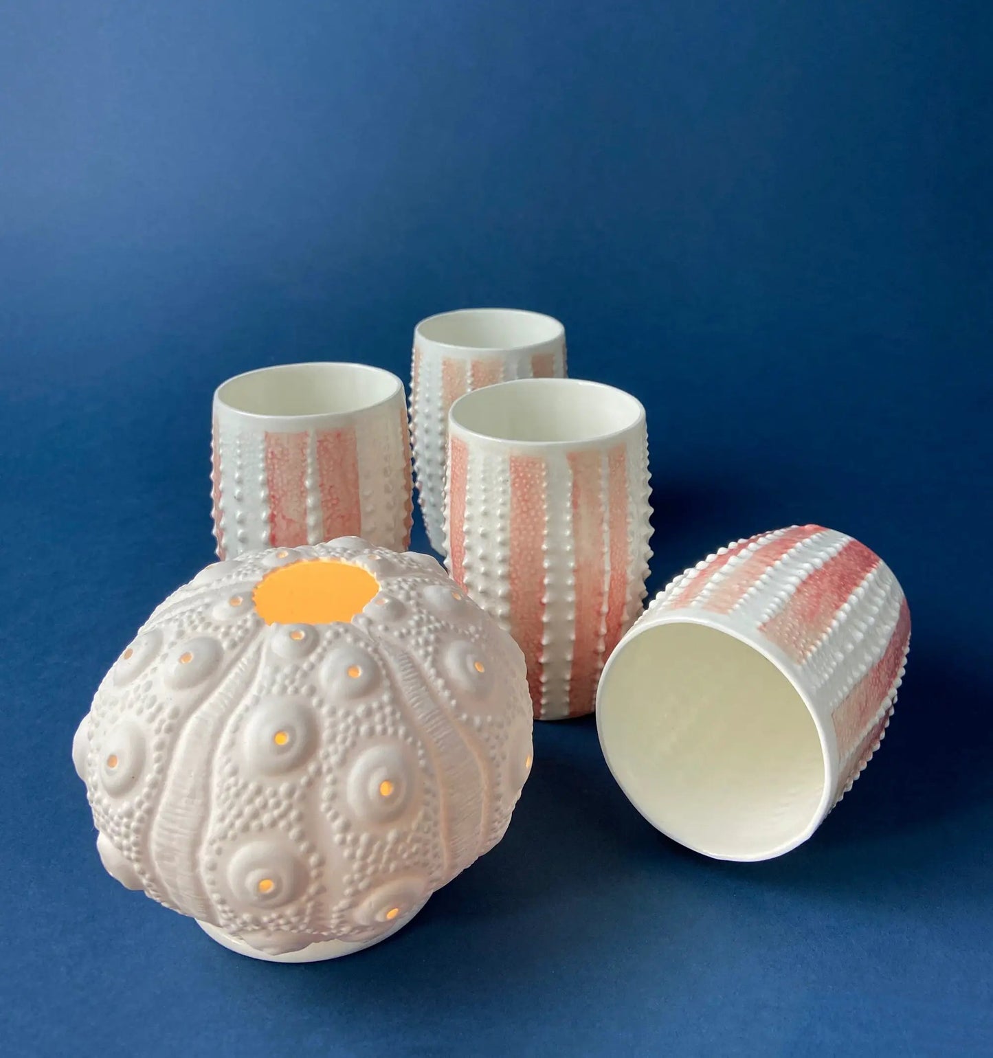 Whitewashed ceramic cups with pink stripes and dotted texture against blue backdrop on Tampa Home & Garden Store