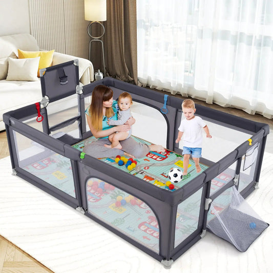 Large gray baby playpen with mat and ocean balls in a living room, mom holds baby, toddler nearby on Tampa Home & Garden Store