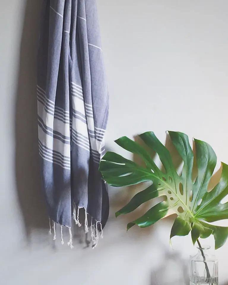Le Boulou Turkish Towel Navy and White, navy striped with fringe, hung next to a Monstera leaf on Tampa Home & Garden Store