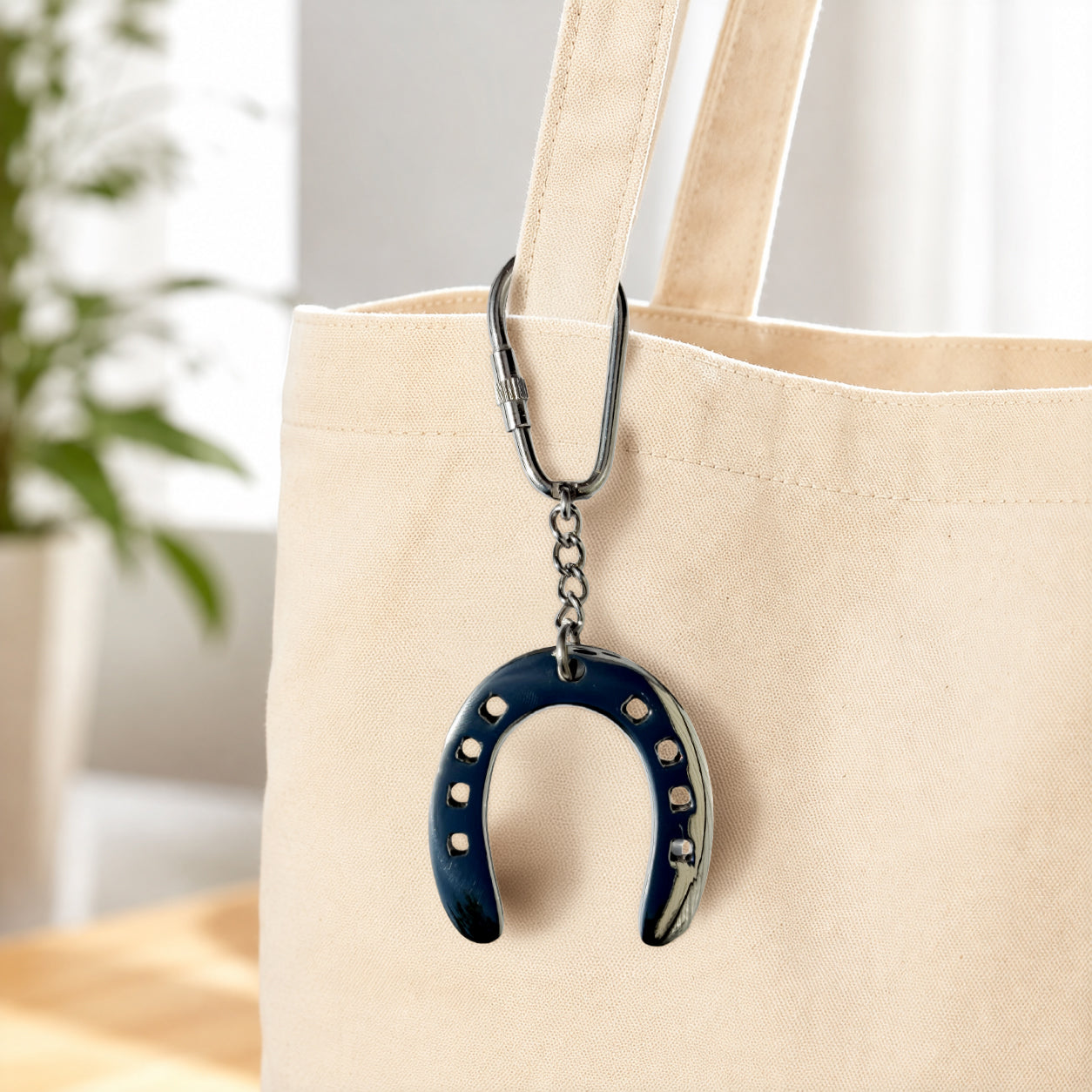Huntley Equestrian blue enamel horseshoe keychain with silver hardware on a beige tote bag on Tampa Home & Garden Store