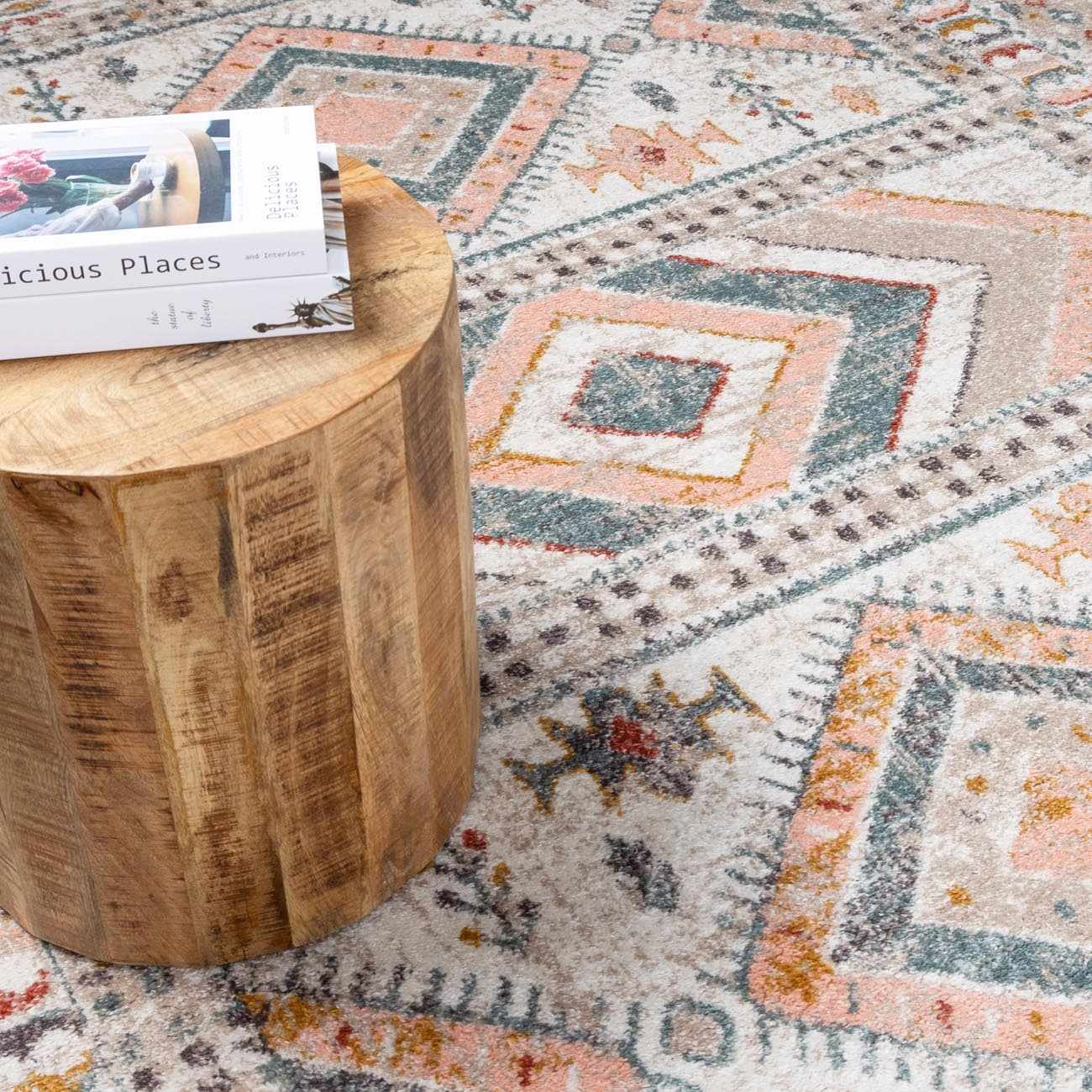 Diem Area Rug by Boutique Rugs with peach geometric pattern; round wood table with two magazines on Tampa Home & Garden Store