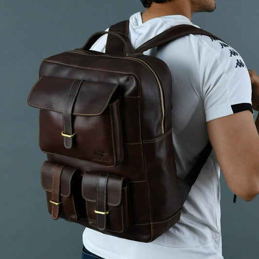 Mahi leather backpack in dark brown with brass hardware and three front pockets worn by a model on Tampa Home & Garden Store