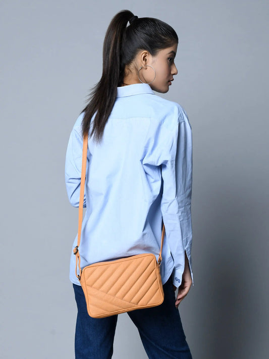 Tan quilted crossbody bag with adjustable strap on model wearing a light blue shirt on Tampa Home & Garden Store