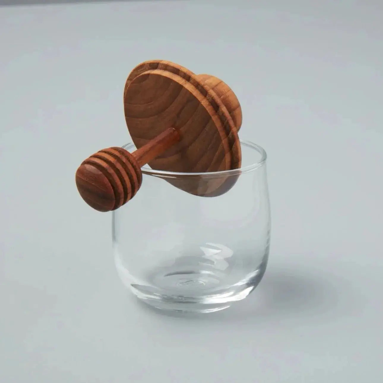 Mini teak and glass honey jar with a wooden honey dipper resting on a clear glass on Tampa Home & Garden Store