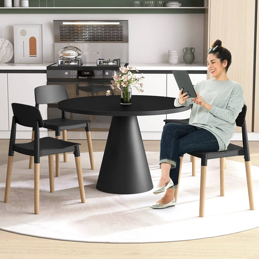 4 black ergonomic dining chairs with wood legs around a round black table in a kitchen on Tampa Home & Garden Store