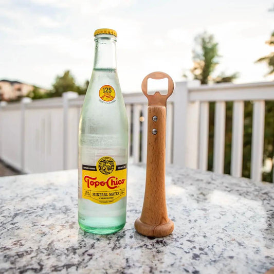 Pickoff Bottle Opener bat-handle stainless steel beside Topo Chico bottle on granite table on Tampa Home & Garden Store