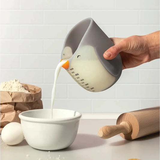 Penny measuring cup by OTOTO DESIGN, penguin-shaped kitchen utensil pouring milk into a bowl on Tampa Home & Garden Store