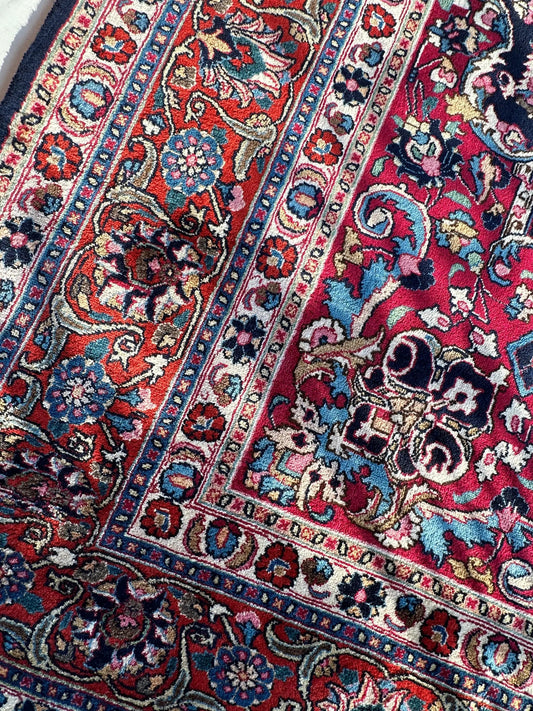 Persian Mashhad hand-knotted distressed wool rug with red and blue floral motifs on Tampa Home & Garden Store