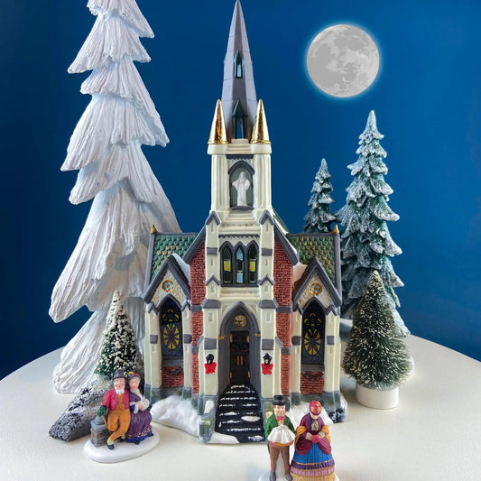 Porcelain Christmas Village Cathedral illuminated with snow-dusted trees and figurines on Tampa Home & Garden Store