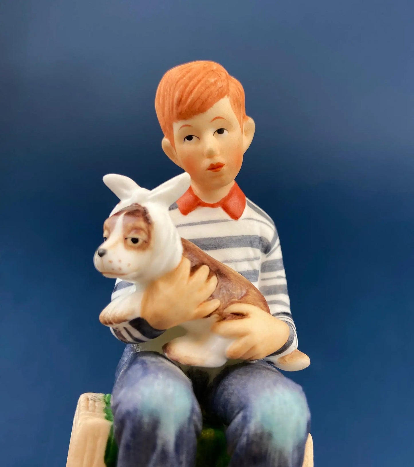 Porcelain boy figurine holding a white and brown dog, striped shirt, orange hair, blue jeans on Tampa Home & Garden Store