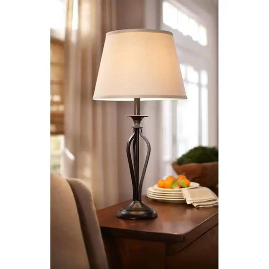 Bronze table lamp with beige linen shade and sculpted metal base on wooden table on Tampa Home & Garden Store