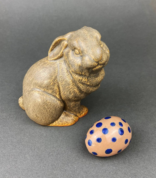 Beige ceramic bunny figurine with textured fur beside a pink dotted Easter egg on Tampa Home & Garden Store