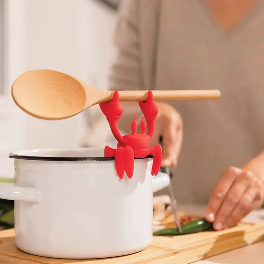Ototo Red lobster-shaped silicone utensil rest gripping a wooden spoon above a white pot on Tampa Home & Garden Store