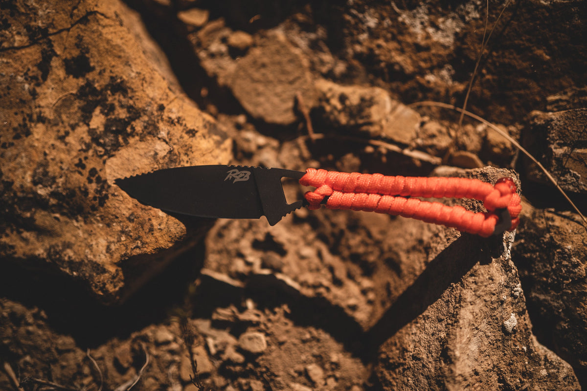 Ultralight Ridge Blade knife by Ridge Belts with black blade and orange paracord handle on rocks on Tampa Home & Garden Store