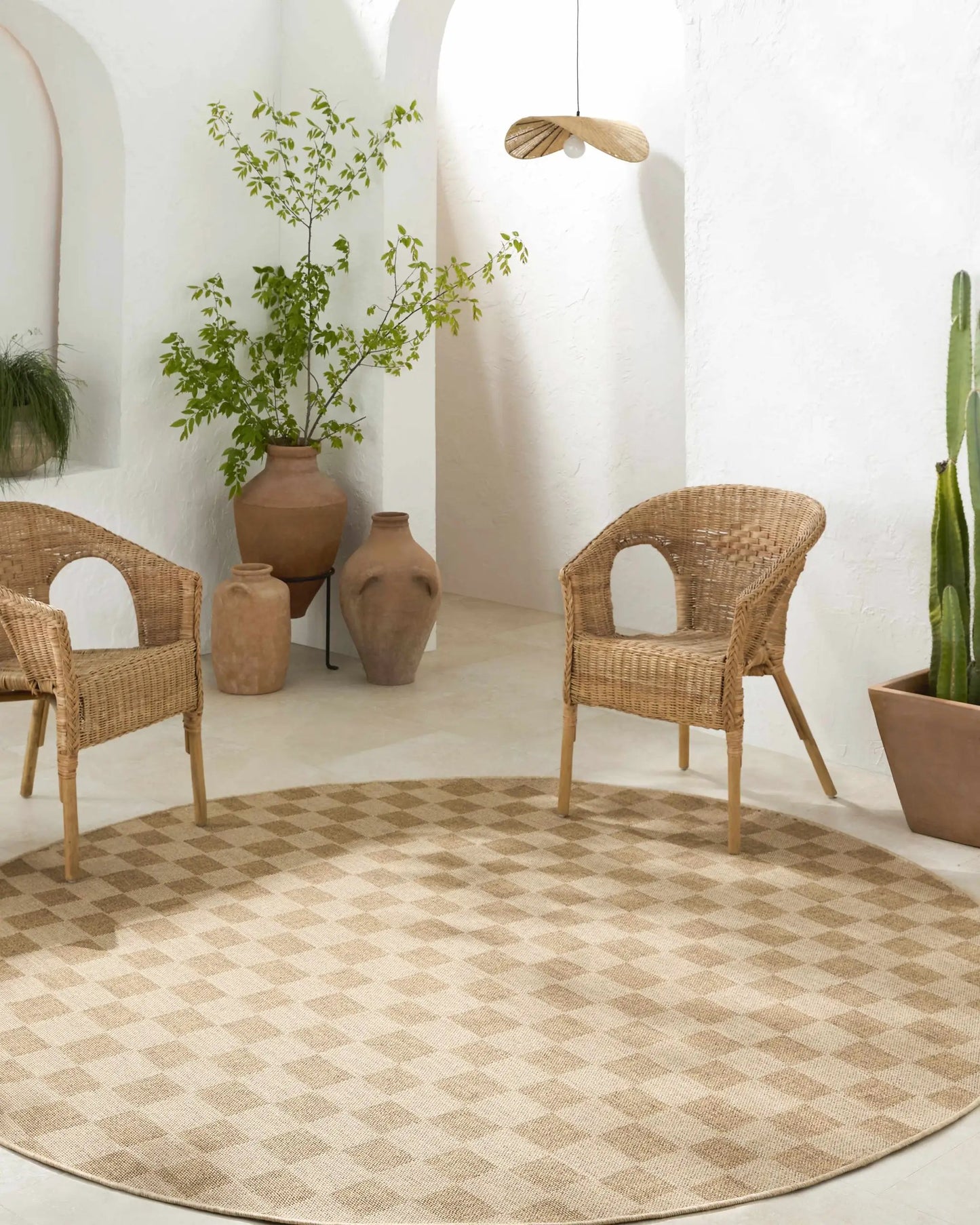 Kuval checkered brown outdoor rug runner by Boutique Rugs on a sunlit patio with wicker chairs on Tampa Home & Garden Store