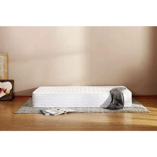 Full-size Talalay latex mattress with quilted white cover on a gray rug in a minimalist bedroom on Tampa Home & Garden Store