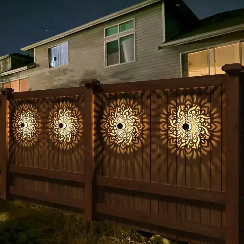 Solar Hollow Outdoor Wall Light set of 3 casts sunburst patterns on a wooden fence at night on Tampa Home & Garden Store