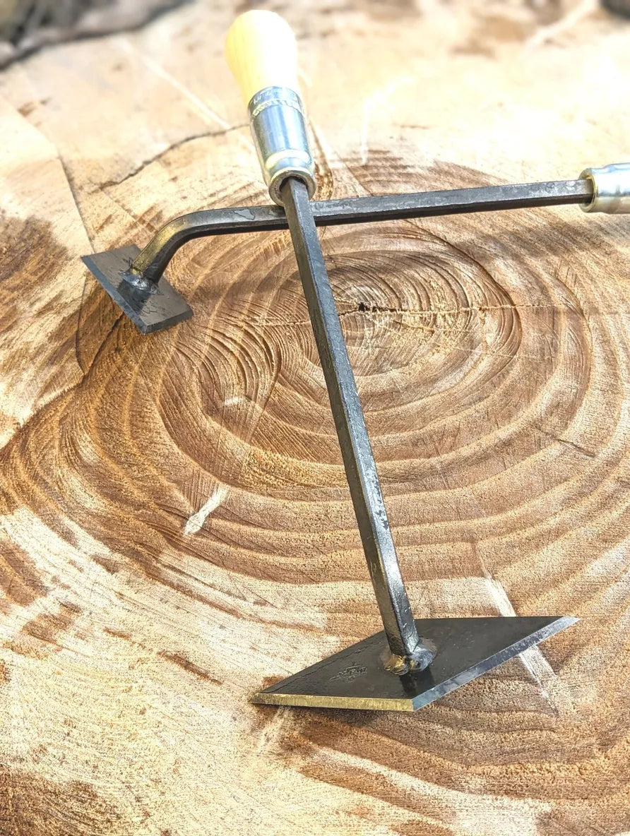 Homestead Iron scuffle weeder with wooden handle and iron head on a tree stump on Tampa Home & Garden Store