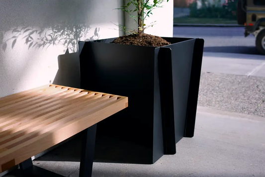 Stahl Planter in black powder-coated steel with angular panels beside a slatted bench on Tampa Home & Garden Store