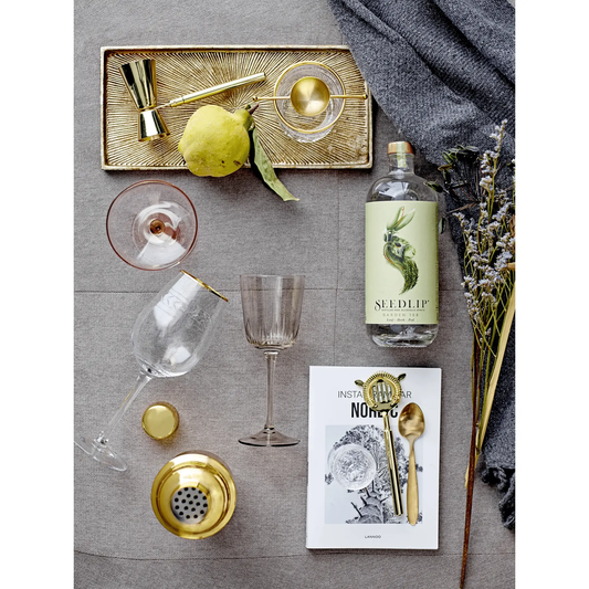 Brass-finish stainless steel cocktail shaker with matching jigger and bar spoon on textured tray on Tampa Home & Garden Store