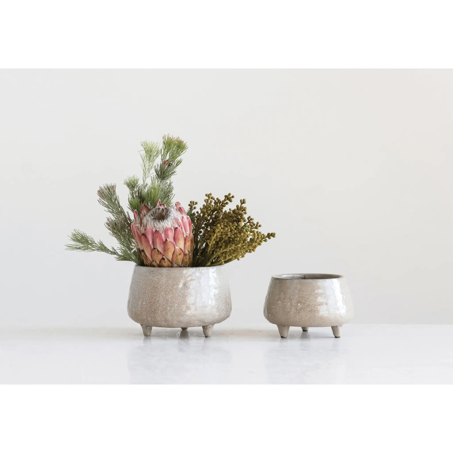 Stoneware footed planters, 2 with beige speckled glaze holding a floral arrangement on Tampa Home & Garden Store