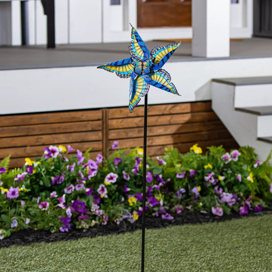 Swallowtail Butterfly Metal Wind Spinner 48in stake with blue and yellow wings in a flower bed on Tampa Home & Garden Store