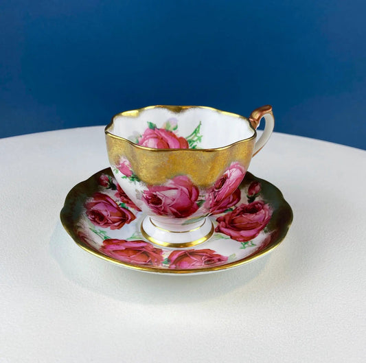 Teacup and saucer with pink roses and gold rim on white porcelain with blue backdrop on Tampa Home & Garden Store