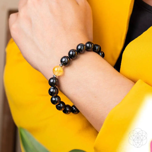 Arfvedsonite Deep Healing Bracelet for Renewal with black beads and a single amber bead on the wrist on Tampa Home & Garden Store