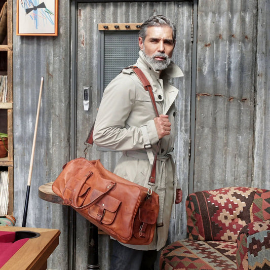 Hydrus Carry-On Duffle Bag vintage brown leather with crossbody strap worn by man in trench coat on Tampa Home & Garden Store