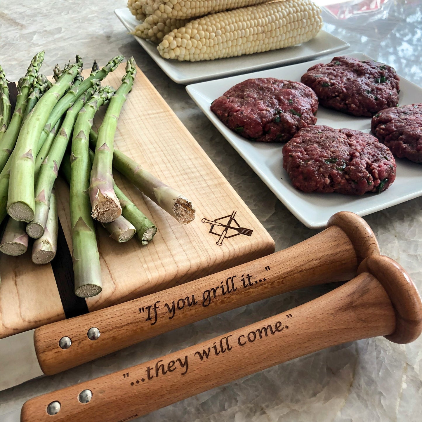 Triple Play Grill Set Custom Handles BBQ tools on wooden board beside asparagus and patties on Tampa Home & Garden Store