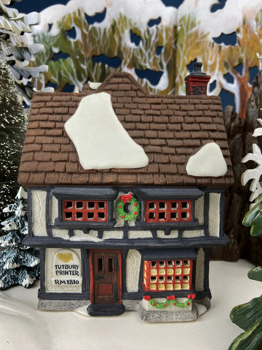 Tutbury Printer Christmas Village House with snow on brown shingled roof and red lattice windows on Tampa Home & Garden Store
