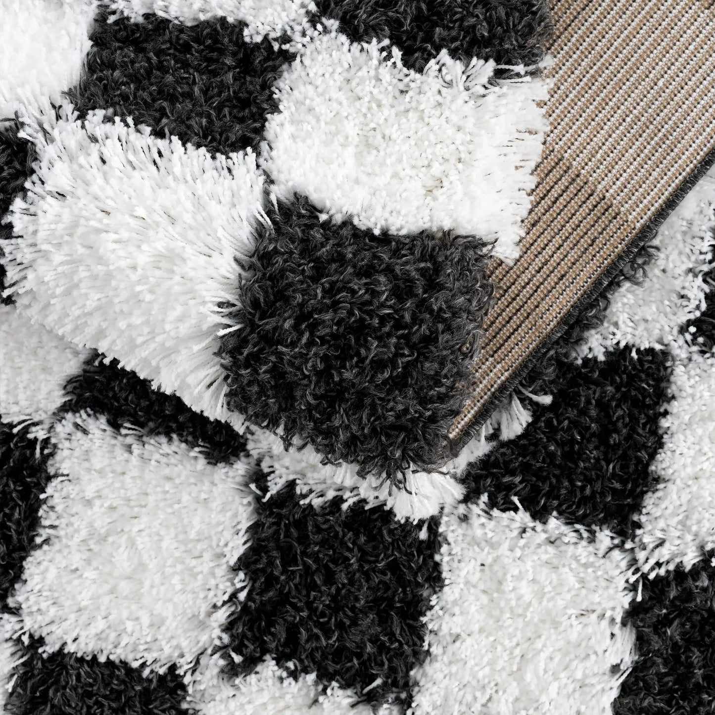 Atira black and white checkered area rug close-up showing plush shag texture and woven border on Tampa Home & Garden Store