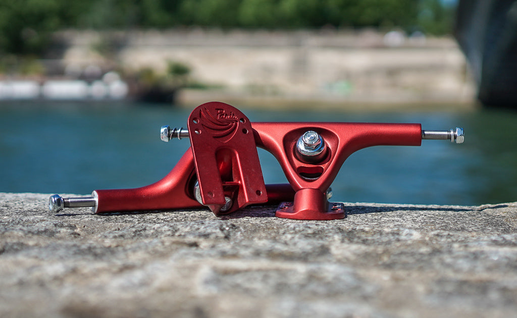 Longboard trucks V3 180mm 50° scarlet red by Paris Truck Co with hardware on concrete near water on Tampa Home & Garden Store
