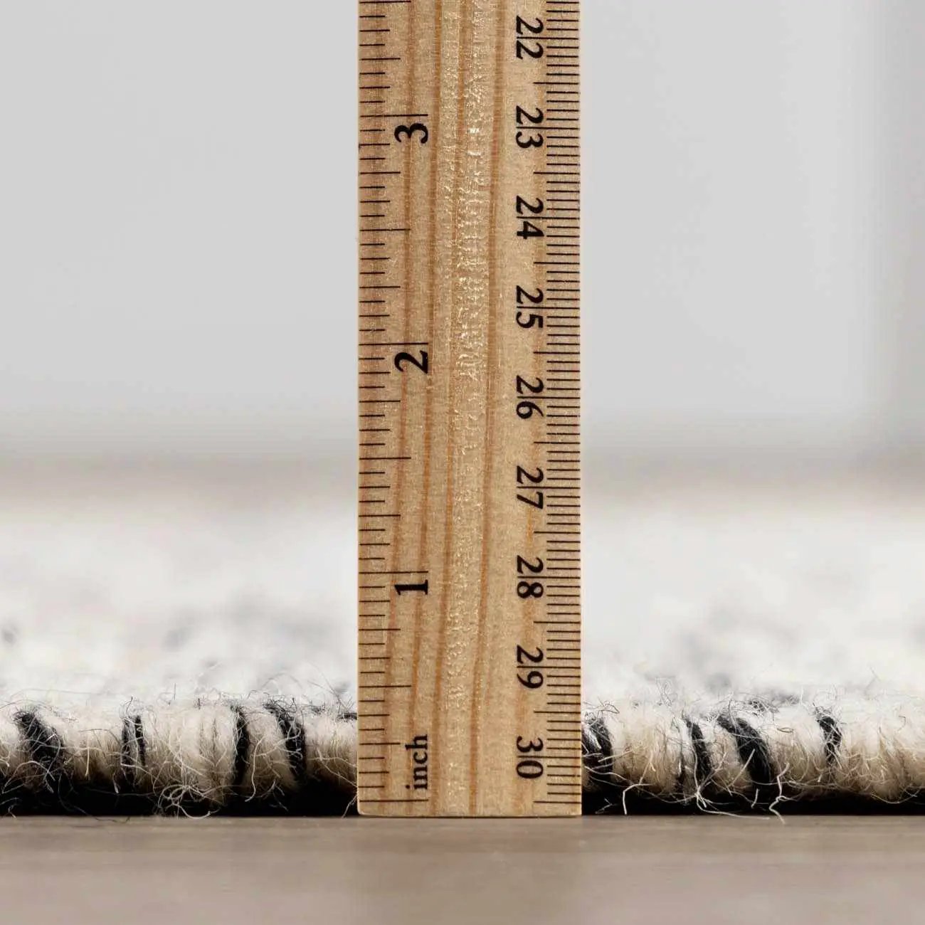 Williford Wool Area Rug with wooden ruler showing its low pile height in cream wool on Tampa Home & Garden Store