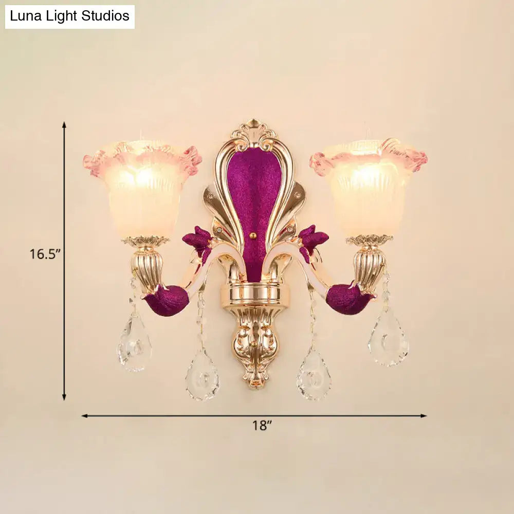 Gold double-arm wall sconce with purple velvet backplate, crystal drops and pink frosted glass shades on Tampa Home & Garden Store