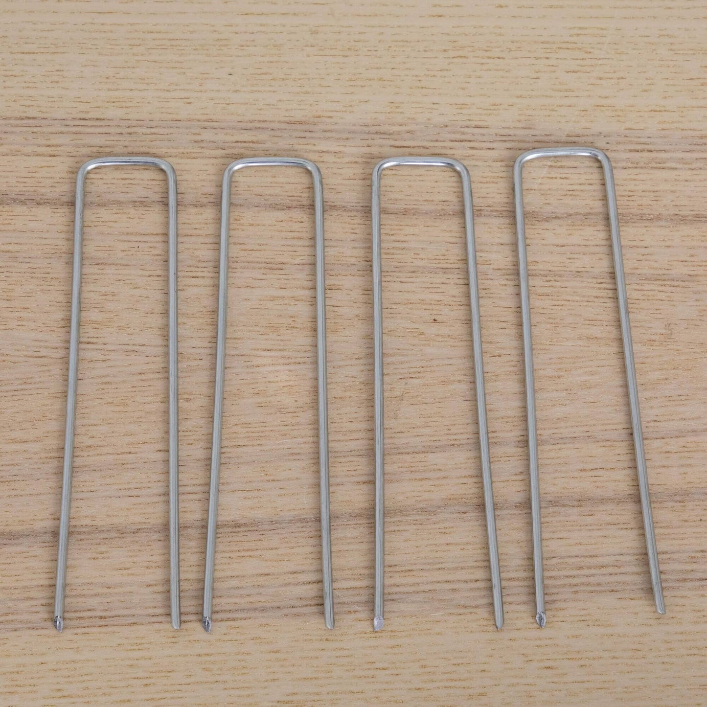 Silver U-shaped metal garden stakes arranged on a wooden surface on Tampa Home & Garden Store