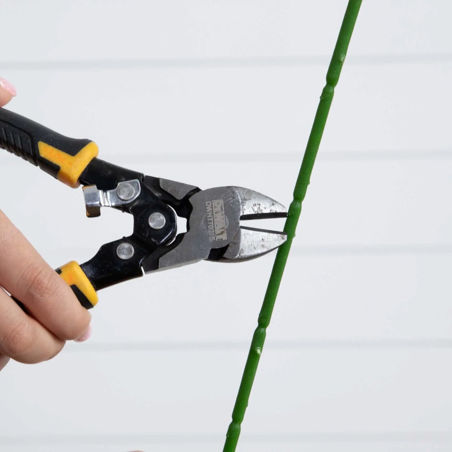 33-inch artificial Stargazer Lily stem in vibrant green being trimmed with pliers on Tampa Home & Garden Store